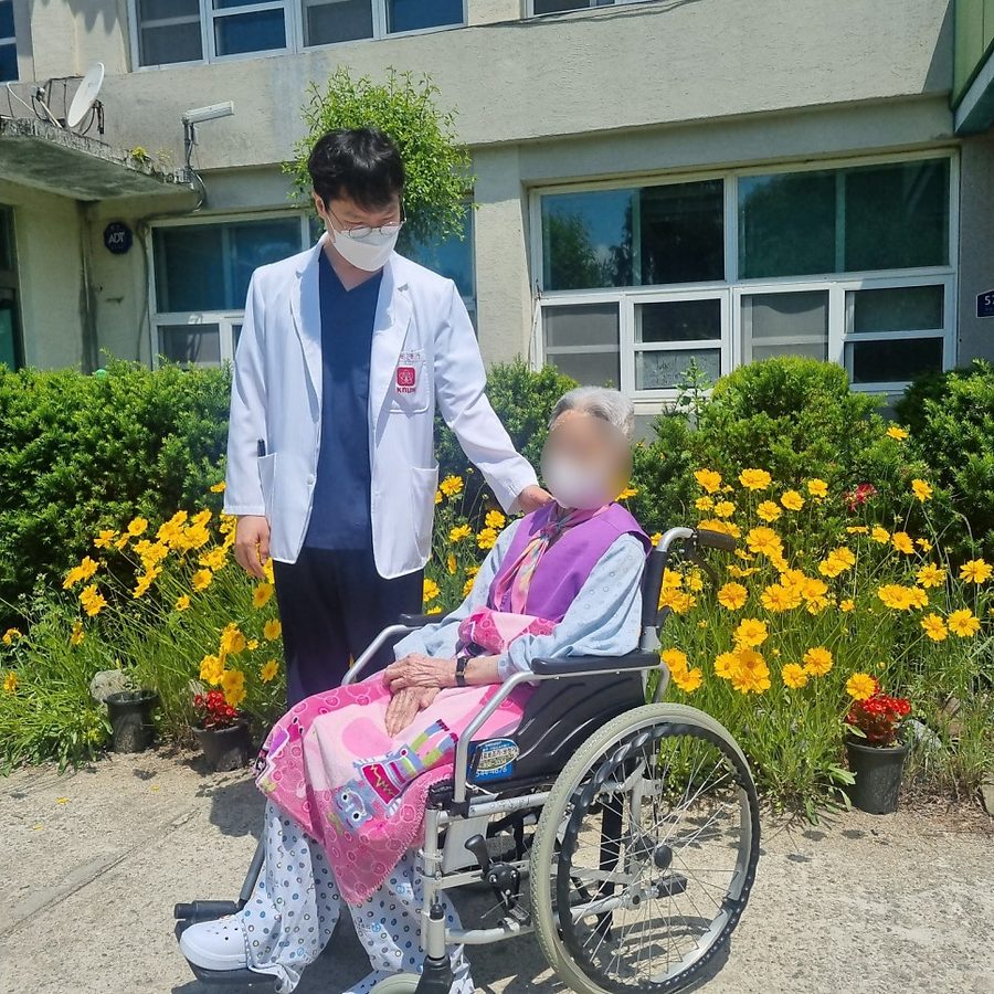 의료진이 휠체어에 앉은 어르신과 함께 정원에 나와 있는 모습